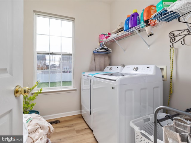 laundry area featuring a wealth of natural light, washer and dryer, and light hardwood / wood-style flooring