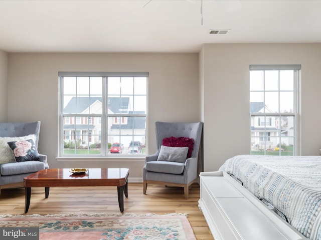 bedroom featuring ceiling fan, multiple windows, and light hardwood / wood-style floors