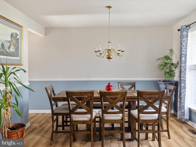 dining space with hardwood / wood-style flooring and a chandelier