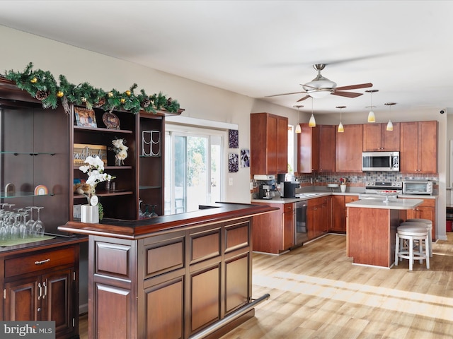 kitchen with a breakfast bar area, light hardwood / wood-style flooring, appliances with stainless steel finishes, and a center island