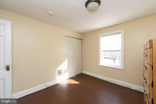 unfurnished bedroom with a closet and dark wood-type flooring