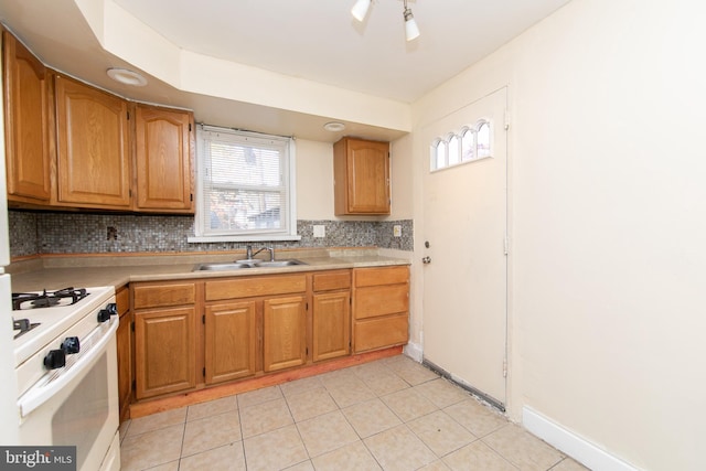 kitchen with white range with gas cooktop, decorative backsplash, sink, and light tile patterned floors