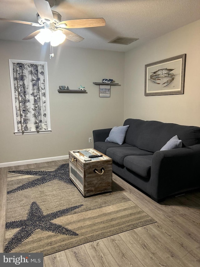 living room with a textured ceiling, hardwood / wood-style flooring, and ceiling fan