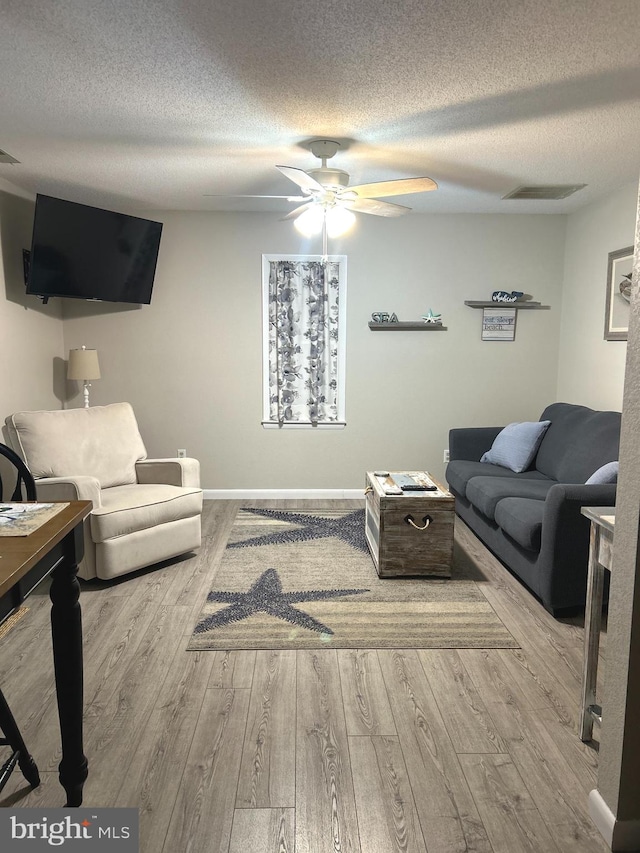 living room featuring a textured ceiling, ceiling fan, and light hardwood / wood-style flooring