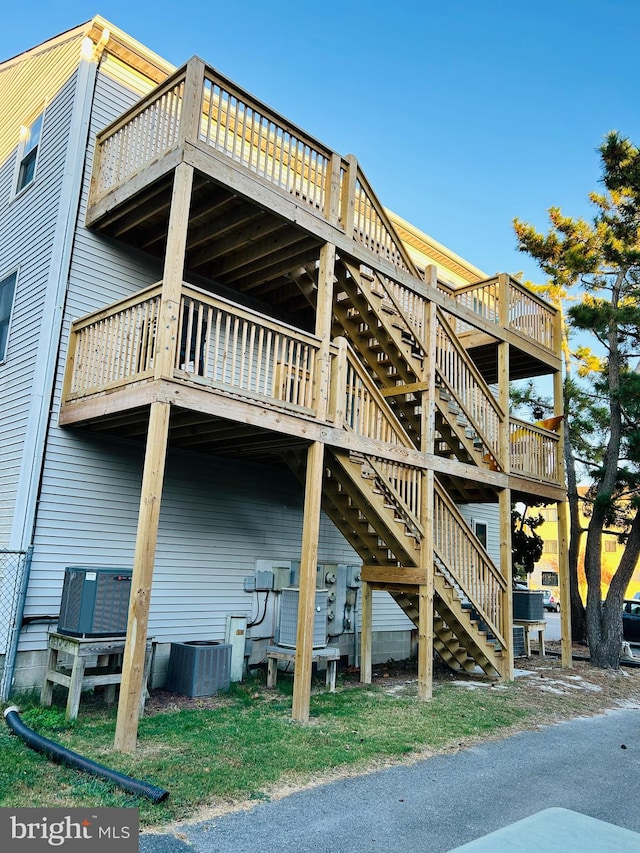 back of property with a wooden deck and central AC