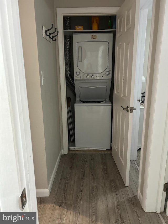 clothes washing area with stacked washer and clothes dryer and wood-type flooring