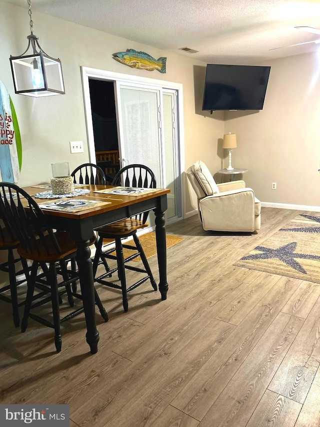 dining space with wood-type flooring and a textured ceiling