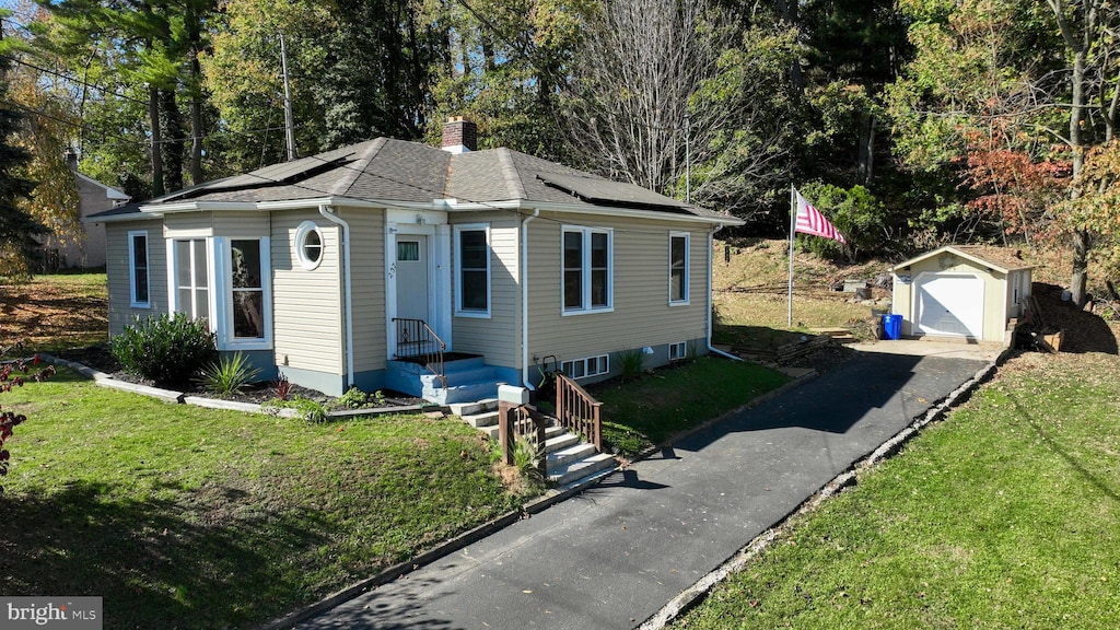 view of front of property with a front lawn, a shed, and a garage