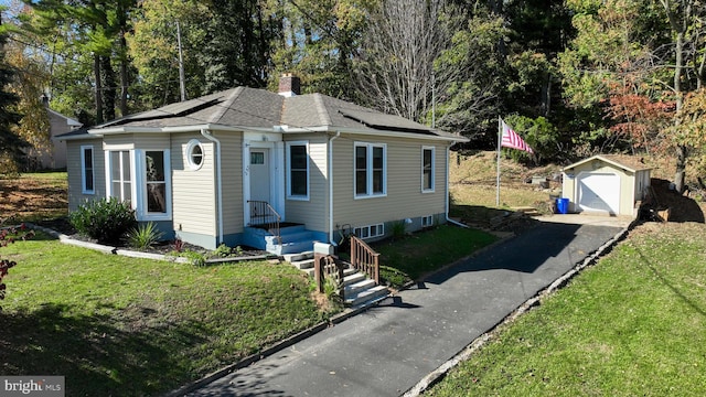 view of front of property with a front lawn, a shed, and a garage