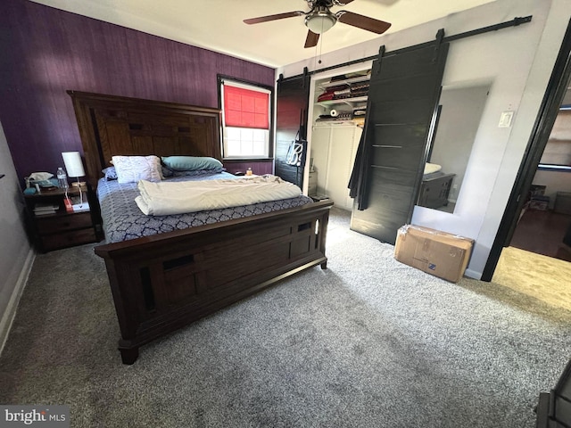 bedroom featuring a barn door, ceiling fan, and dark carpet