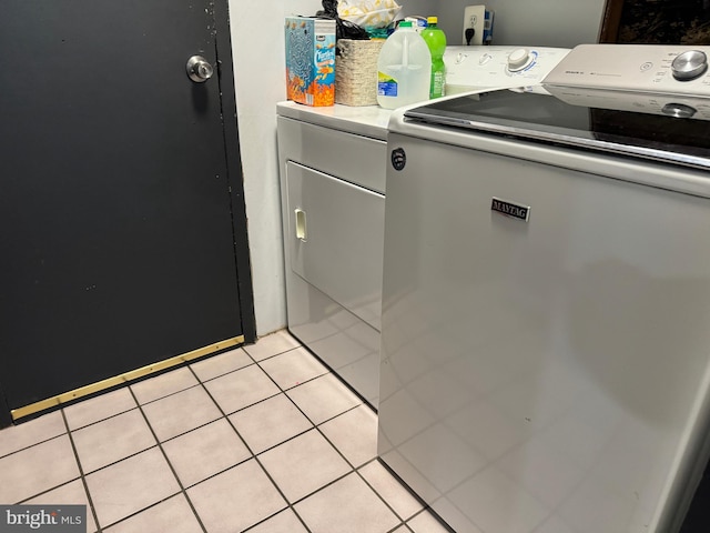 clothes washing area with independent washer and dryer and light tile patterned floors