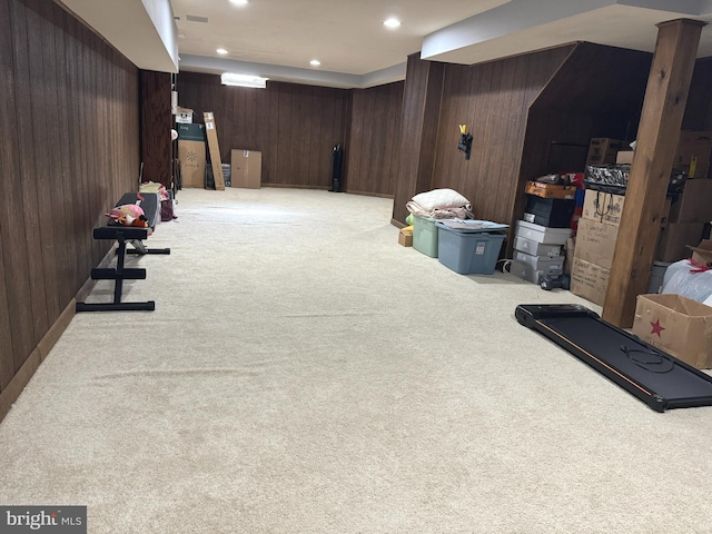 basement featuring light colored carpet and wood walls