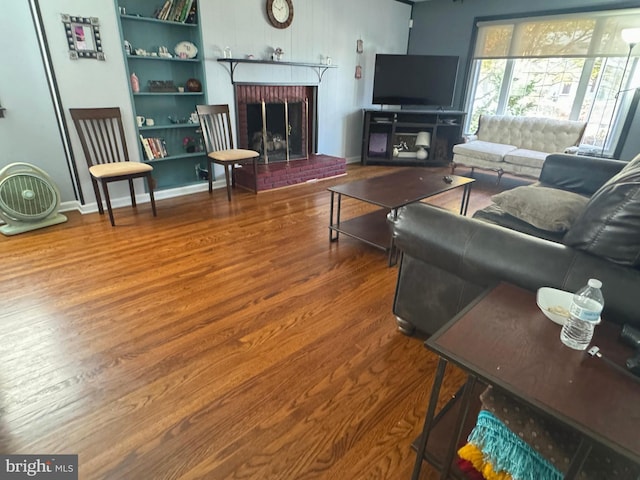 living room with a brick fireplace and hardwood / wood-style flooring