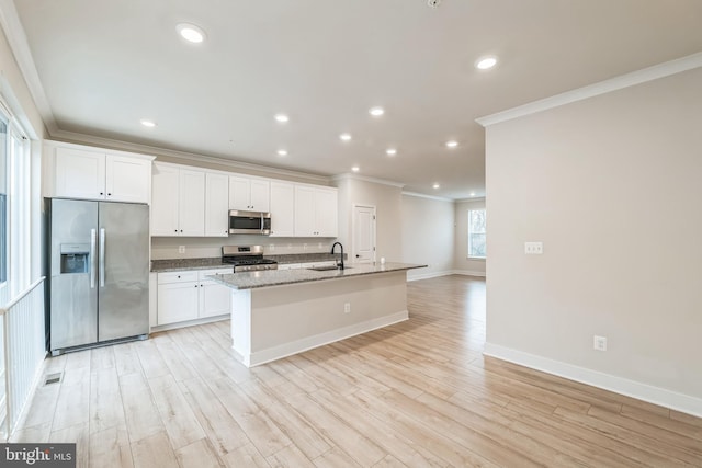 kitchen featuring light hardwood / wood-style flooring, white cabinets, an island with sink, and stainless steel appliances