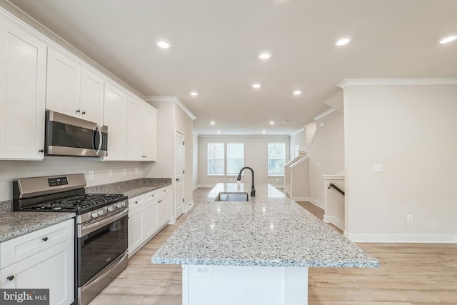 kitchen with white cabinets, sink, a kitchen island with sink, and appliances with stainless steel finishes