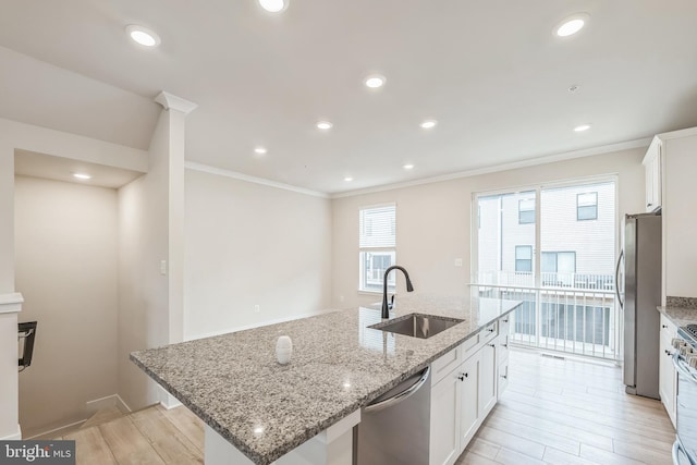 kitchen featuring stainless steel appliances, white cabinets, sink, an island with sink, and light hardwood / wood-style flooring