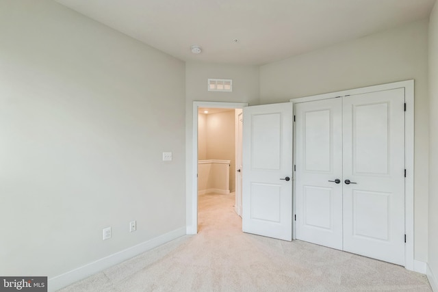 unfurnished bedroom featuring light colored carpet and a closet