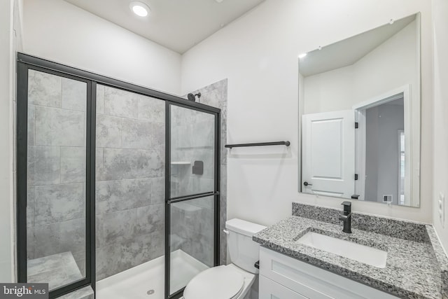 bathroom featuring toilet, vanity, and a shower with door