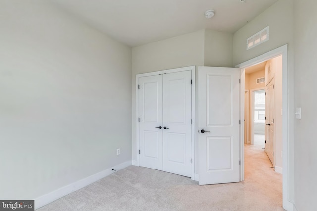 unfurnished bedroom with light carpet and a closet