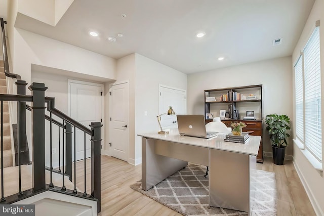 office space with light hardwood / wood-style floors and a healthy amount of sunlight