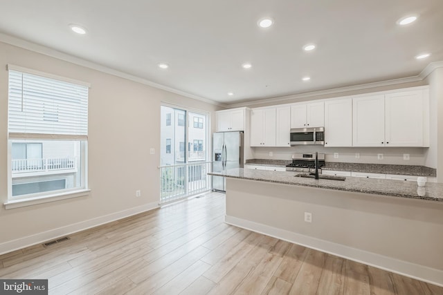 kitchen with light stone countertops, appliances with stainless steel finishes, ornamental molding, and white cabinets