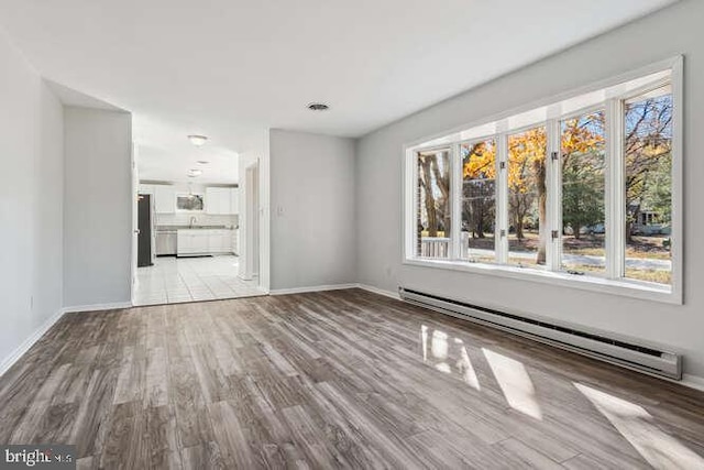 unfurnished living room featuring baseboard heating and light hardwood / wood-style flooring