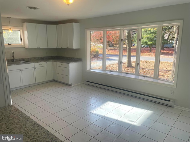 kitchen featuring white cabinets, a baseboard radiator, a healthy amount of sunlight, and sink