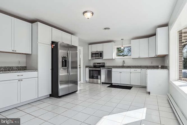 kitchen with white cabinets, light tile patterned flooring, appliances with stainless steel finishes, and a baseboard radiator