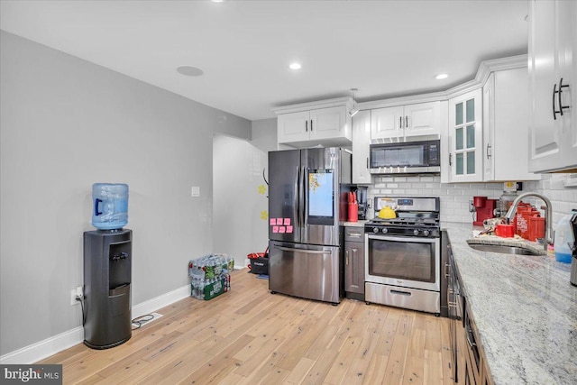 kitchen featuring light hardwood / wood-style floors, sink, appliances with stainless steel finishes, light stone countertops, and white cabinets