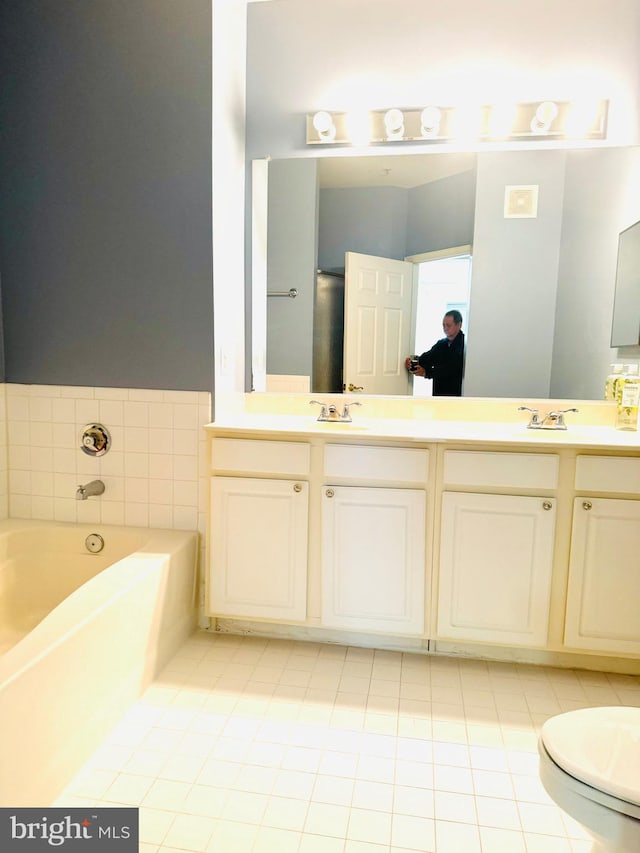 bathroom featuring tile patterned floors, vanity, a bath, and toilet