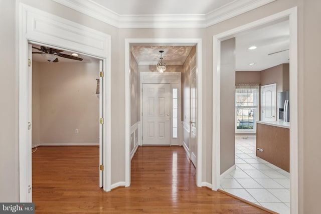 foyer entrance with ceiling fan, crown molding, and light wood-type flooring