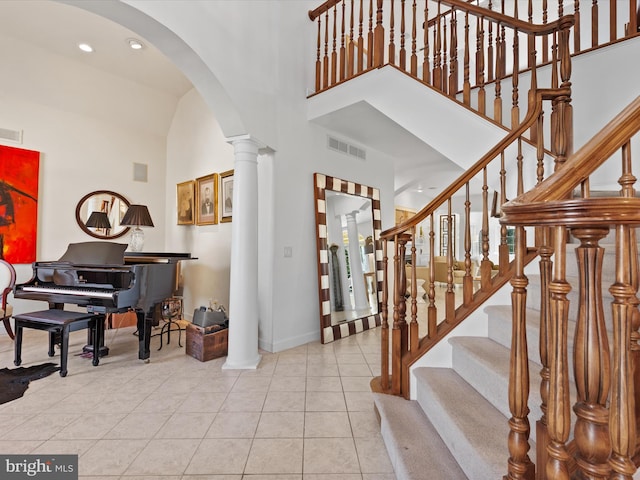 foyer with high vaulted ceiling, light tile patterned floors, and decorative columns