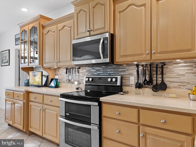 kitchen with light brown cabinetry, decorative backsplash, light tile patterned floors, and stainless steel appliances