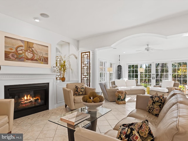 tiled living room featuring ceiling fan and decorative columns