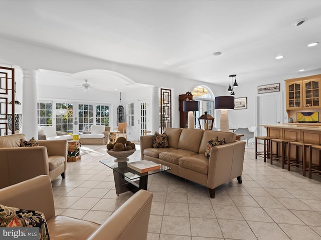 tiled living room featuring ornate columns, french doors, plenty of natural light, and ceiling fan