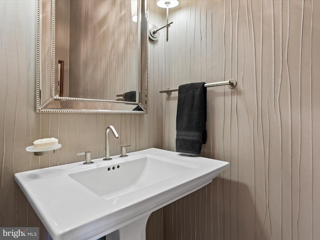 bathroom featuring wood walls and sink