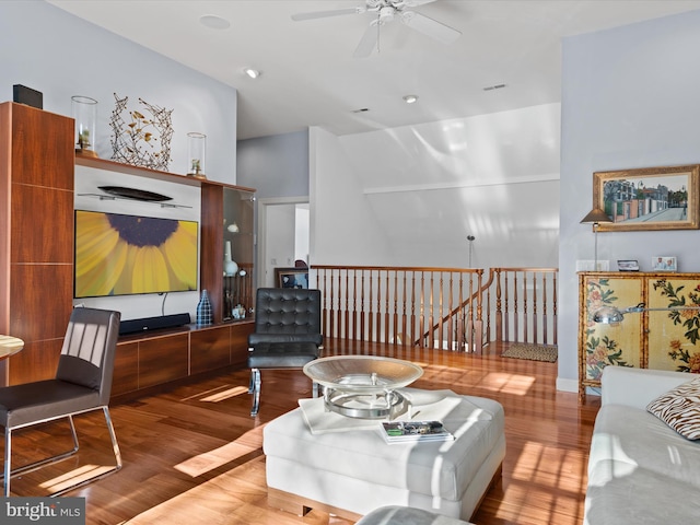 living room with hardwood / wood-style flooring, ceiling fan, and vaulted ceiling