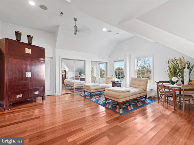 living room with light hardwood / wood-style floors, ceiling fan, and vaulted ceiling