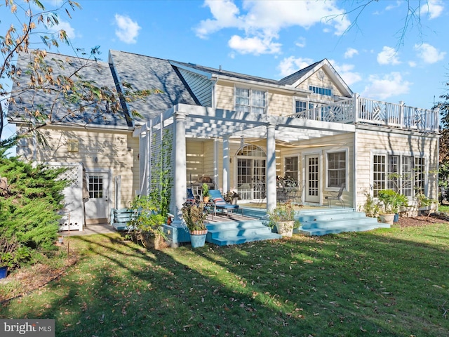 rear view of house with a balcony, a lawn, and a pergola