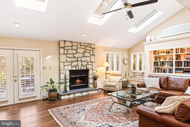 living room with dark hardwood / wood-style flooring, high vaulted ceiling, a stone fireplace, and a baseboard radiator