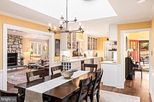 dining area with ornamental molding, a fireplace, dark hardwood / wood-style flooring, and sink