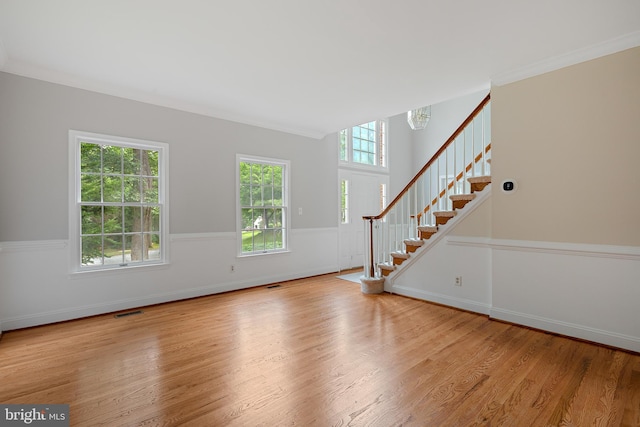 unfurnished living room with ornamental molding and light hardwood / wood-style floors