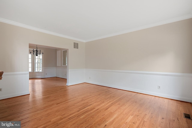 spare room featuring crown molding, a chandelier, and light hardwood / wood-style floors