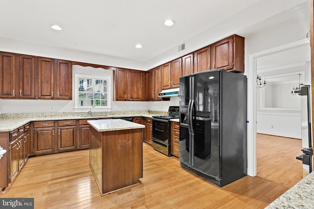 kitchen featuring light stone counters, sink, black appliances, and a kitchen island