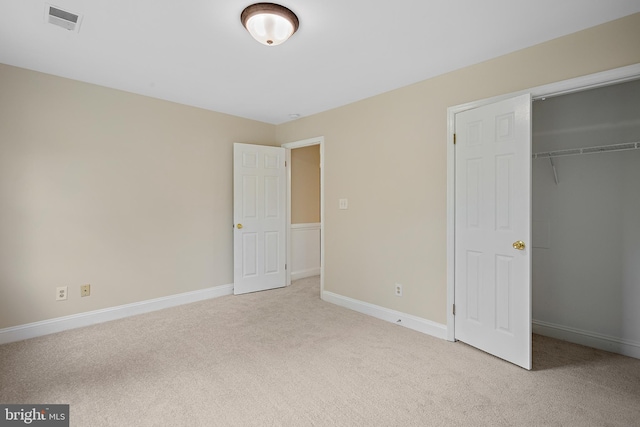 unfurnished bedroom featuring light colored carpet and a closet