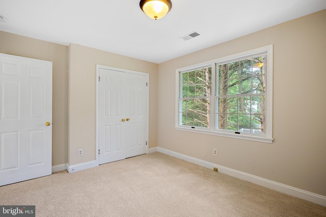 unfurnished bedroom featuring a closet and light carpet