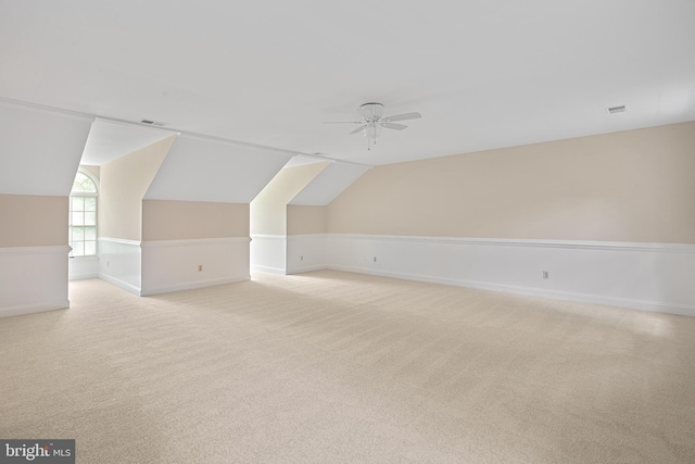 additional living space with vaulted ceiling, light colored carpet, and ceiling fan