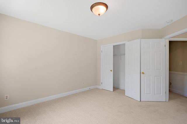 unfurnished bedroom with light colored carpet and a closet