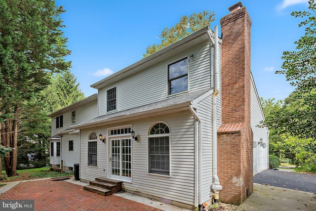 rear view of house with a garage and a patio