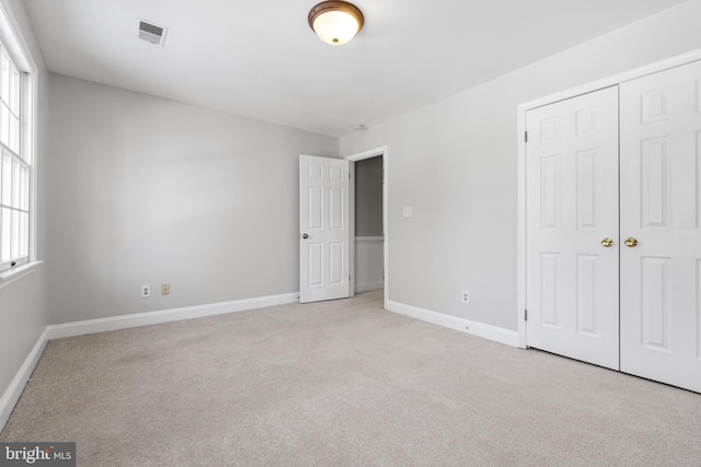 unfurnished bedroom featuring light carpet and a closet